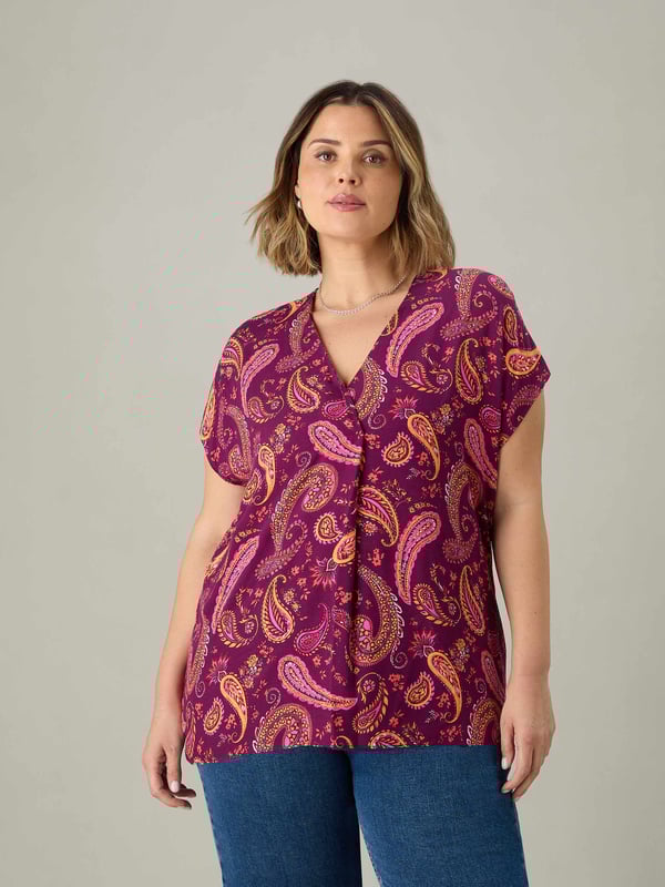 In a pretty purple-red paisley print, this pleat front top is cut from a lightweight woven fabric thats so comfortable to wear. With a lengthening V-neck, this top has short sleeves and pleat detailing through the centre front which complements its loose, A-line body. Pair this with jeans or leggings for the perfect laid-back look.