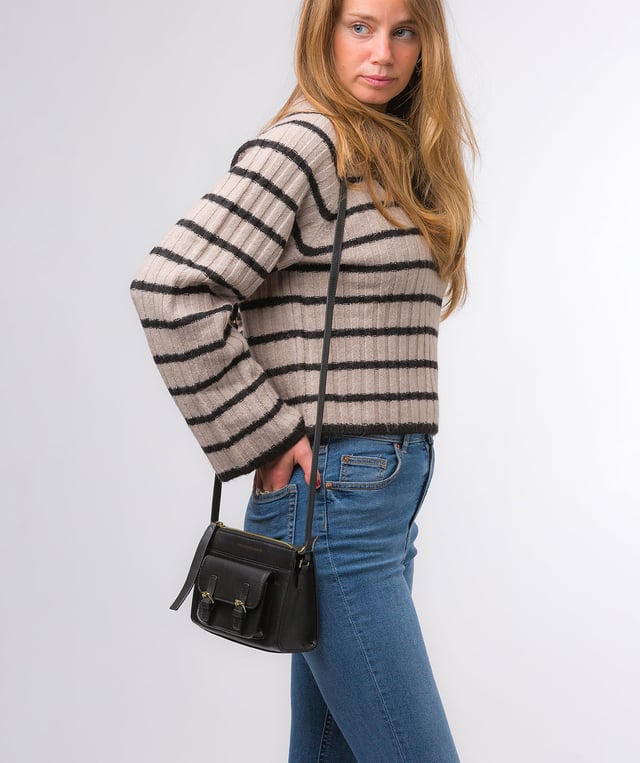 Handcrafted from Nappa leather, the 'Monica' cross body bag from the Pure Luxuries London Marylebone Collection elevates this classic design. A spacious main compartment is secured under a zip-over top which is lined with 100% cotton for a luxurious feel. Two slip pockets on the interior of the bag provide additional storage space - ideal for maintaining an organised accessory. Complementing the interior storage is a stylish pocket secured with a press-stud fastener made to look like a buckle reminscent of the classic satchel design. Gold-coloured metal fittings and zips adorn the bag alongside the slim and adjustable leather strap with a maximum drop length of 65cm. The Pure Luxuries logo is embossed in gold foil for a beautifully simple finishing touch.