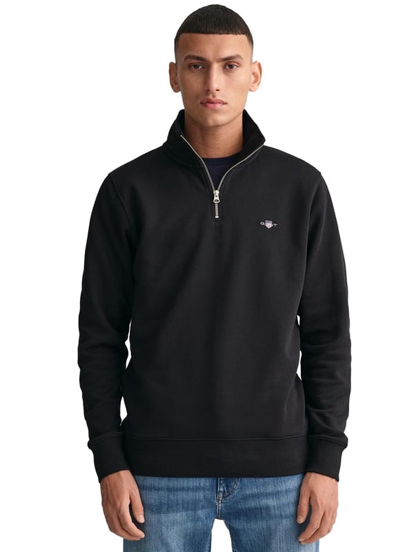 This versatile half-zip sweatshirt combines comfort and style with a premium cotton-polyester blend that's perfect for transitional weather. Featuring a small, intricately embroidered GANT graphic on the chest, it showcases a subtle yet elevated design. The ribbed hem and cuffs create a tailored silhouette. Designed for a regular fit, the half-zip collar adds a touch of sporty elegance, while the durable fabric ensures long-lasting wear.