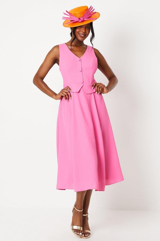 Elegant waistcoat-style bodice with button detailing
        Flattering V-neckline and sleeveless design
        Graceful midi length with a flowing drape skirt
        Sophisticated crepe fabric for a polished look
        Versatile silhouette suitable for various formal occasions
    
    Embody refined elegance with this captivating waistcoat midi dress. The structured bodice, adorned with delicate buttons, creates a striking contrast against the gracefully draped skirt, offering a harmonious blend of tailored sophistication and feminine fluidity. Perfect for weddings, race days, or any upscale event, this dress commands attention without compromising on comfort. Style it with strappy metallic heels and a coordinating fascinator for a quintessentially British look. For cooler evenings, drape a lightweight pashmina over your shoulders. Accessorise with understated jewellery to maintain the dress's clean lines and let its exquisite design take centre stage. This versatile piece transitions effortlessly from day to evening, making it a valuable addition to your occasion wear wardrobe.