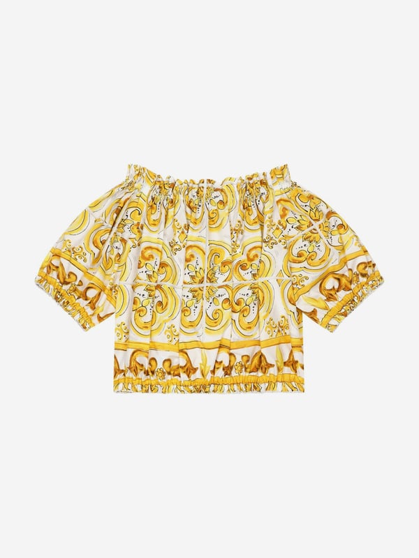 Dolce & Gabbana utilise new technological properties to create captivating aesthetics. This girls blouse is a part of the FW24/25 Girl‚  Collection. Depicted in Majolica, a symbol of Italian craftsmanship, it comes in lemon yellow, brightened up by pure white, taking inspiration from Sicilian pottery. Envisioned in cotton poplin with all-over yellow majolica print via a cropped fit and short puff sleeves, showcasing elasticated cuffs.  Made in Italy Boat Neck With Dropped Shoulders Stretch Hem Placed Print Due to "Handmade" Aspect 100% Cotton