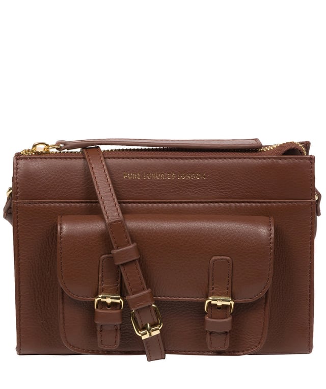 Handcrafted from Nappa leather, the 'Monica' cross body bag from the Pure Luxuries London Marylebone Collection elevates this classic design. A spacious main compartment is secured under a zip-over top which is lined with 100% cotton for a luxurious feel. Two slip pockets on the interior of the bag provide additional storage space - ideal for maintaining an organised accessory. Complementing the interior storage is a stylish pocket secured with a press-stud fastener made to look like a buckle reminscent of the classic satchel design. Gold-coloured metal fittings and zips adorn the bag alongside the slim and adjustable leather strap with a maximum drop length of 65cm. The Pure Luxuries logo is embossed in gold foil for a beautifully simple finishing touch.