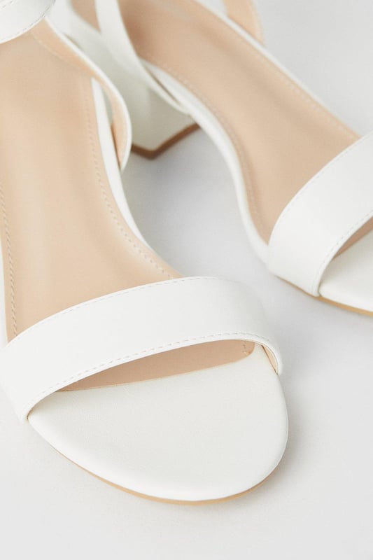 Wide fit design offers a comfortable and accommodating fit
Barely-there strappy silhouette with minimalist appeal
Mid block heel provides a modest lift and walkable height
Faux leather upper exudes a look and feel
Ankle strap with buckle closure ensures a secure fit

These versatile sandals are perfect for casual daytime outings or relaxed evening affairs. Pair them with a flowy midi dress or cropped trousers for a chic, on-trend look that transitions seamlessly from brunch with friends to an evening baby shower. The neutral hue complements a variety of ensembles, allowing you to showcase your personal style effortlessly.