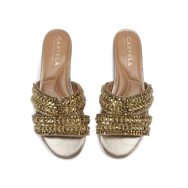 This Carvela Pageant Mule sandal is crafted from a metallic gold fabric and each of the two straps are embellished with statement gold crystals.