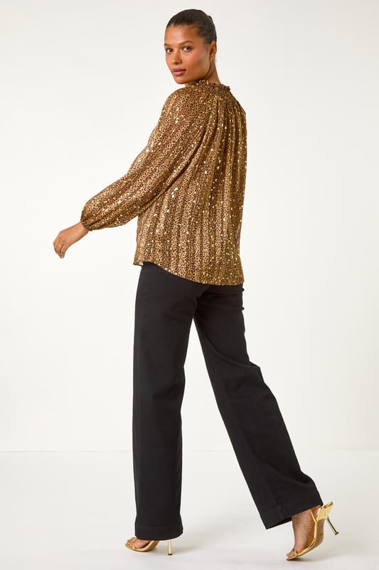 Tie Front Animal Print Blouse from Roman. Embrace your wild side this Autumn/Winter in this stunning animal print blouse. The all over print is elevated with metallic gold spots for a touch of glamour, while the V-Neck and button through front create a chic look. Long sleeves keep you warm, and the tie front detail adds a fun twist to this versatile piece. Pair with pleather trousers and heeled boots for a party ready ensemble that's sure to turn heads!