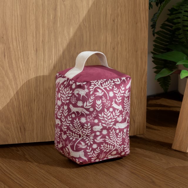 Take a trip to the Scandinavian woodland with this stunning doorstop. Featuring an intricate design of woodland animals from hares to foxes, intertwined with branches in a deep berry tone. This unique design is complemented with a plain velvet dye reverse and puts an ideal finishing touch to a Scandi-style or rustic interior.