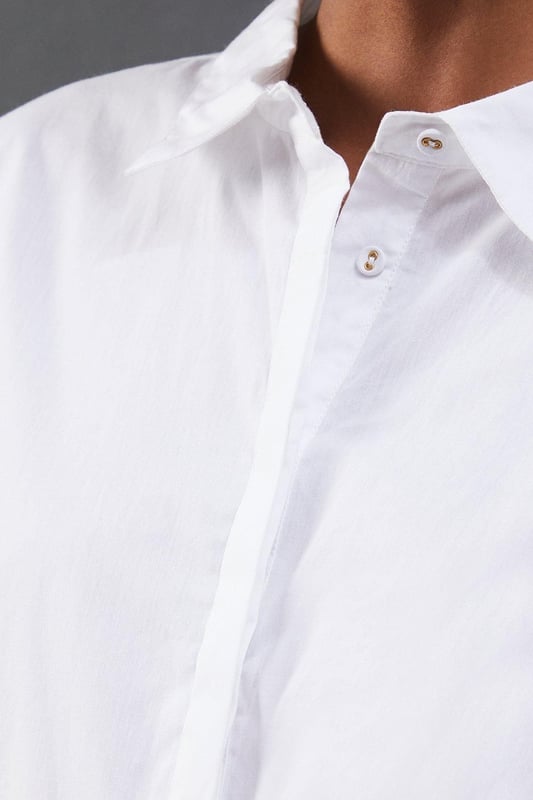 Striking open back design with tie detail
        Classic collared neckline for a polished look
        Long sleeves with button cuffs for versatility
        Relaxed fit through the body for comfort
        Crafted from breathable cotton poplin fabric
    
    Make a statement with this eye-catching poplin shirt from Warehouse. The open back design with delicate tie detail adds an unexpected twist to a classic silhouette, perfect for those who want to inject a bit of edge into their wardrobe. The relaxed fit and breathable cotton fabric ensure all-day comfort, while the collared neckline maintains a smart appearance. Style this versatile piece with your favourite denim for a casual daytime look, or dress it up with tailored trousers for a chic ensemble suitable for family gatherings or brunch with friends. The long sleeves can be rolled up for a more relaxed vibe, making this shirt adaptable for various occasions. Pair with flat sandals or trainers to complete your effortlessly cool outfit.