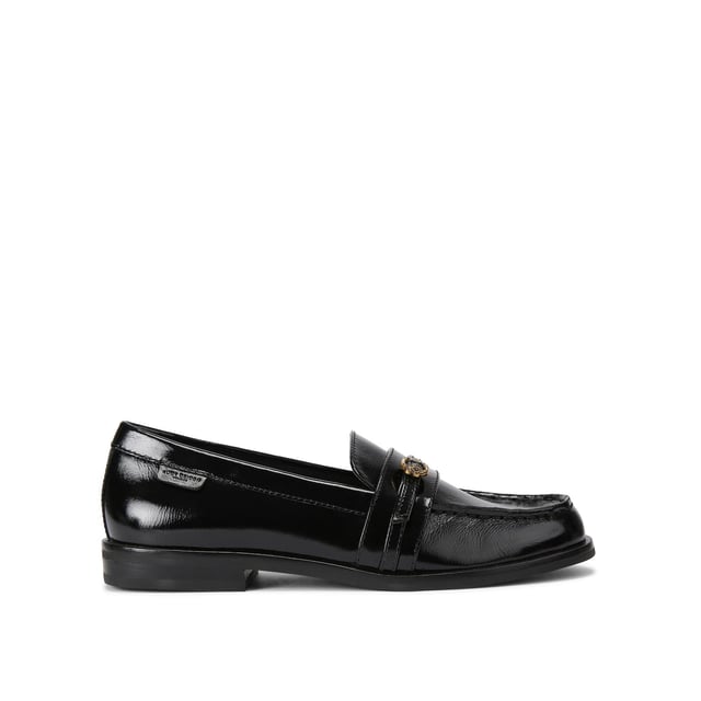The Kurt Geiger Mayfair Slim Loafer features a black patent upper with a thin strap across the toe. There is an antiqued brass buckle with micro eagle head surrounded by crystals fastening the strap.