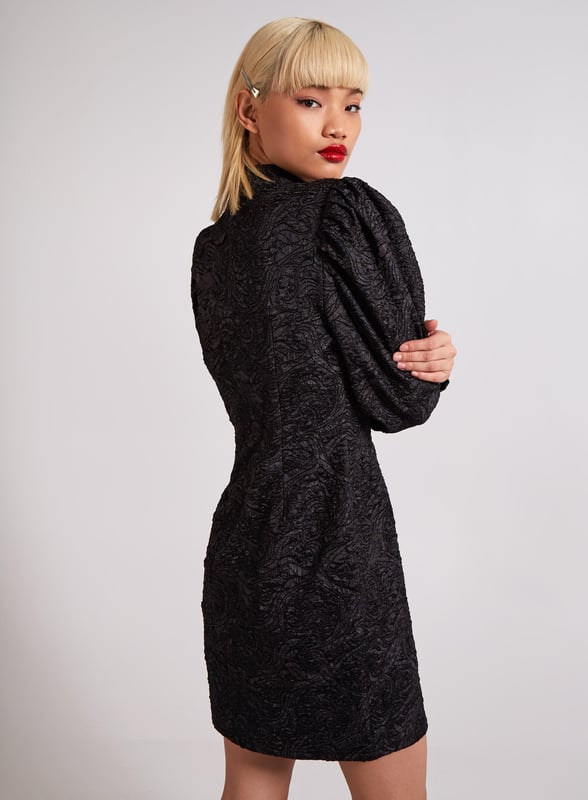 If you want to make an entry this season this dress is the one to do it in. Featuring a embossed black fabric, a high neck design with long sleeves and a flattering cut. Composition: 100% Polyester. Wash care: Machine Washable.
