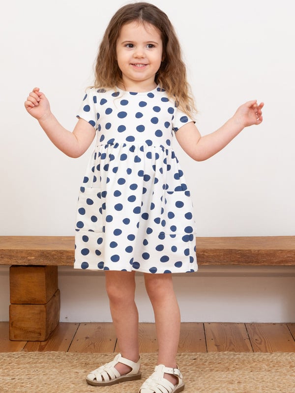 95% organic cotton 5% elastane | Proud to be certified to the Global Organic Textile Standard (GOTS) | Big spot all-over print | Cream and navy blue | French terry loop back fabric (240-250 gsm) | Coconut button shoulder opening (up to and including size 3 years) | Patch pockets | Short sleeved | Round neck | Made in Turkey | Machine washable at 40 degrees, or at 30 degrees to be kinder to the planet