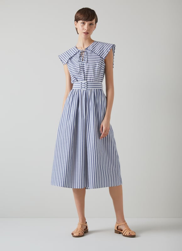A chic sun dress which takes design cues from sailor style, beautiful Beau is destined for glamorous destinations. It's crafted from blue and cream striped cool cotton, and has a wide scalloped edge collar with tie detail, a fabric-covered buckle belt and an A-line midi skirt. Wear it with a pair of leather sandals and a basket bag.