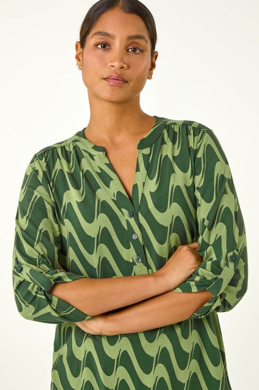Geometric Print Stretch Blouse from Roman. Elevate your wardrobe this season with our stunning abstract blouse. The bold print and woven silhouette make it versatile for any occasion. The notch neckline, adjustable 3/4 length sleeves and front button details adds a touch of sophistication. Pair it with black jeans and boots for a daytime look or add tailored trousers perfect for those desk-to-dinner days
