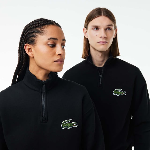 Unisex Lacoste Loose Fit High Neck Sweatshirt in Black. Finest materials, brand’s singular expertise. The perfect expression of Lacoste’s timeless wardrobe.- Loose fit is loose ease on body and sleeves, lower shoulders and armholes.- Half zipped sweatshirt in organic heavy French terry with big croc 80' on chest.- Unisexe.- Zipped high collar in shell fabric.- 7cm iconic original badge crocodile.- 3cm green crocodile at under middle back collar. Material: 100% Organic Cotton. Ref: SH0069031.