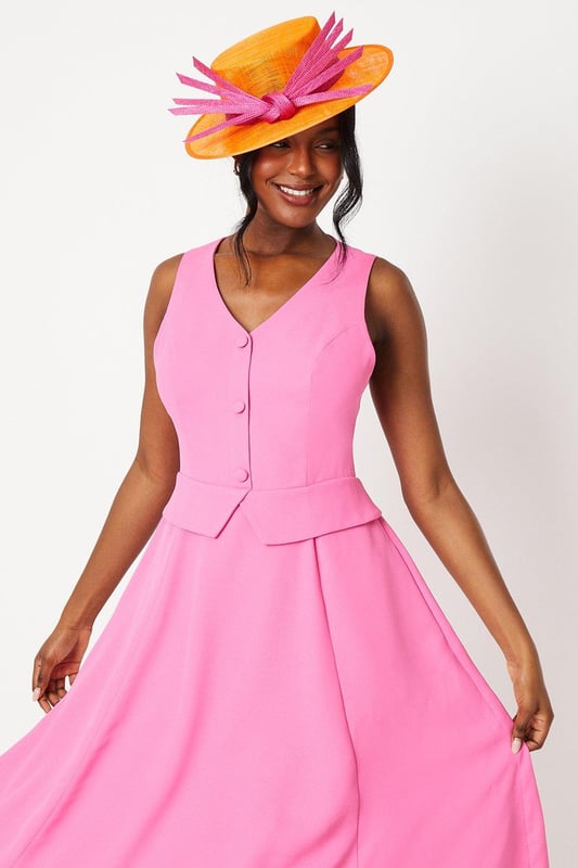 Elegant waistcoat-style bodice with button detailing
        Flattering V-neckline and sleeveless design
        Graceful midi length with a flowing drape skirt
        Sophisticated crepe fabric for a polished look
        Versatile silhouette suitable for various formal occasions
    
    Embody refined elegance with this captivating waistcoat midi dress. The structured bodice, adorned with delicate buttons, creates a striking contrast against the gracefully draped skirt, offering a harmonious blend of tailored sophistication and feminine fluidity. Perfect for weddings, race days, or any upscale event, this dress commands attention without compromising on comfort. Style it with strappy metallic heels and a coordinating fascinator for a quintessentially British look. For cooler evenings, drape a lightweight pashmina over your shoulders. Accessorise with understated jewellery to maintain the dress's clean lines and let its exquisite design take centre stage. This versatile piece transitions effortlessly from day to evening, making it a valuable addition to your occasion wear wardrobe.