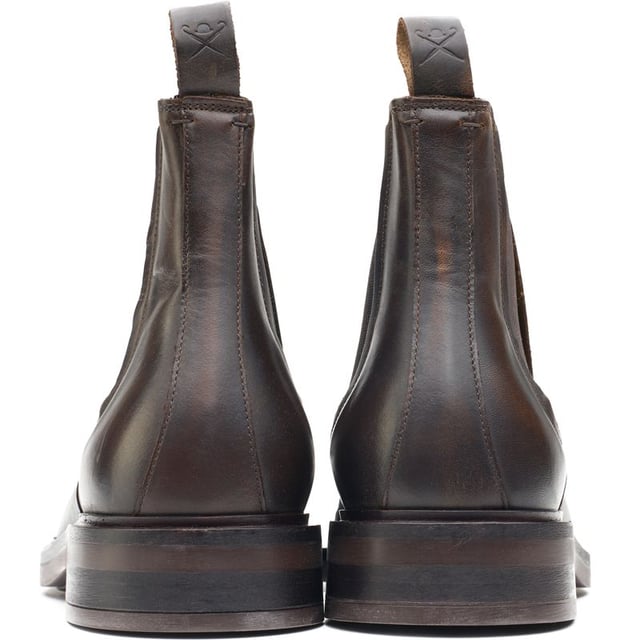 Preséntese en la ciudad con una sofisticación elegante con estas botas Hackett London Egmont. Estas botas Chelsea clásicas, confeccionadas a mano en Portugal, cuentan con una parte superior de cuero de lujo con refuerzos elásticos y un monograma H cosido a mano que adorna cada lado, mientras que la plantilla de cuero extraíble le brinda comodidad al pie en cada paso y la lengüeta de cuero en relieve le agrega un estilo característico.