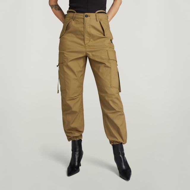 Flap pockets at the waist and back- hidden snap button. Cargo pockets at the thigh- hidden snap closure. Adjustable leg hem- Integrated tape. Zip & button closure. High waist. Cargo pants Drawcord show a straight fit with a shortened length. The straps at the back allow for a tighter waist. The pleats at the knee add more shape. The cargo pockets show an additional pull strap. 70% Cotton, 30% Cotton (Recycled). Canvas woven. Peach finish, soft touch. Straight