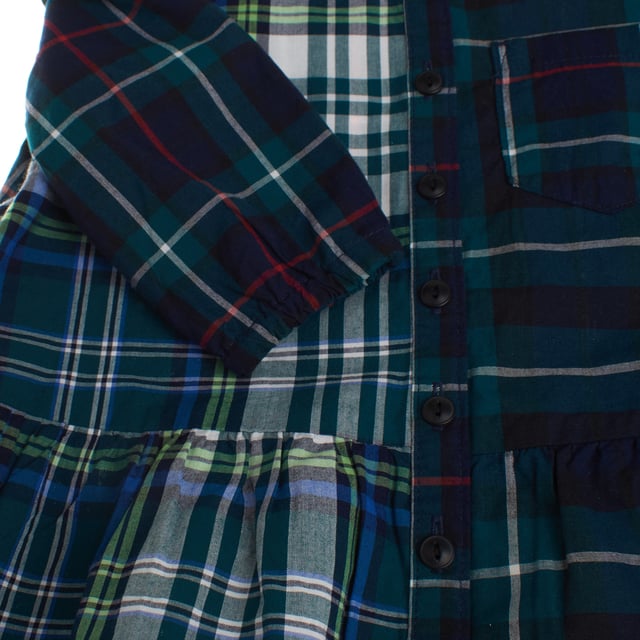 This shirt dress perfectly combines classic and modern style.

 Made of soft flannel fabric, it stands out for its checkered design in different patterns, which create an original and striking contrast.

 The round neckline, adorned with subtle gathers, adds a delicate touch, while the front button closure maintains the functional and timeless essence of this type of garment.

 It features a patch pocket on the chest, a practical and decorative style that attaches to the garment without closures or flaps.

 Long sleeves with elastic cuffs ensure a comfortable fit, and the layered skirt adds movement and a dynamic touch.

 Ideal for a casual yet stylish look, this dress is a versatile option and perfect for everyday wear.
 Composition: 100% Cotton
 Care:
- Hand wash or delicate cycle.
 - Use mild detergents.
 - Do not use a dryer.
 - Iron at low temperature.
 - Do not dry clean.