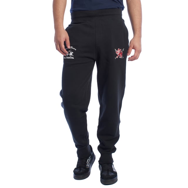 Pantalón de chándal para hombre de La Martina.

Estilo y elegancia se combinan en este pantalón deportivo de La Martina, diseñado para los hombres que buscan comodidad sin renunciar a un diseño exclusivo. 

Detalles:

- Fabricado en algodón de alta calidad, suave y transpirable, para garantizar comodidad durante todo el día.
- Cintura elástica que asegura un ajuste cómodo y seguro en cualquier actividad.
- Bordados exclusivos de La Martina en ambos lados del pantalón, destacando el logotipo y un león rojo icónico que aportan un detalle único y sofisticado.
- Bolsillos laterales amplios y funcionales, ideales para guardar pequeños objetos de manera práctica.
- Bolsillo trasero de ribete con bordado decorativo, combinando funcionalidad y estilo elegante.
- Corte relajado con puños en los tobillos.

Este pantalón deportivo hombre de La Martina es la elección ideal para quienes buscan una prenda que combine confort, diseño exclusivo y detalles únicos como sus bordados distintivos. Perfecto para lucir con estilo en el día a día.
 Composición: 100% Algodón
 Cuidados:
- Lavar máximo a 30°C en ciclo suave.
- No usar lejía ni blanqueadores.
- No secar en secadora.
- Planchar a baja temperatura si es necesario, evitando los bordados.