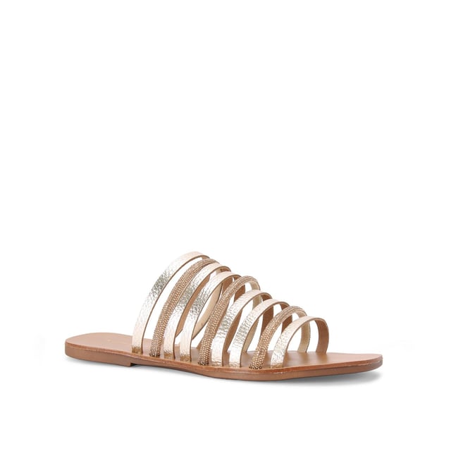 The Kurt Geiger Daisy Flat Sandal is a slip-on sandal. There are multiple gold straps across the upper each with its own metallic finish or crystal embellishment.