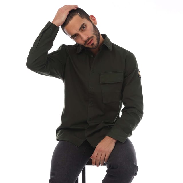 Mens Belstaff Garment Dye Cotton Scale Shirt in green.- Point collar.- Centre front button fastening.- Signature tilted flap pocket.- Adjustable buttoned cuff.- Belstaff Phoenix patch on sleeve.- Garment-dyed cotton twill.- 100% Cotton.- Ref: 104537TLGRN