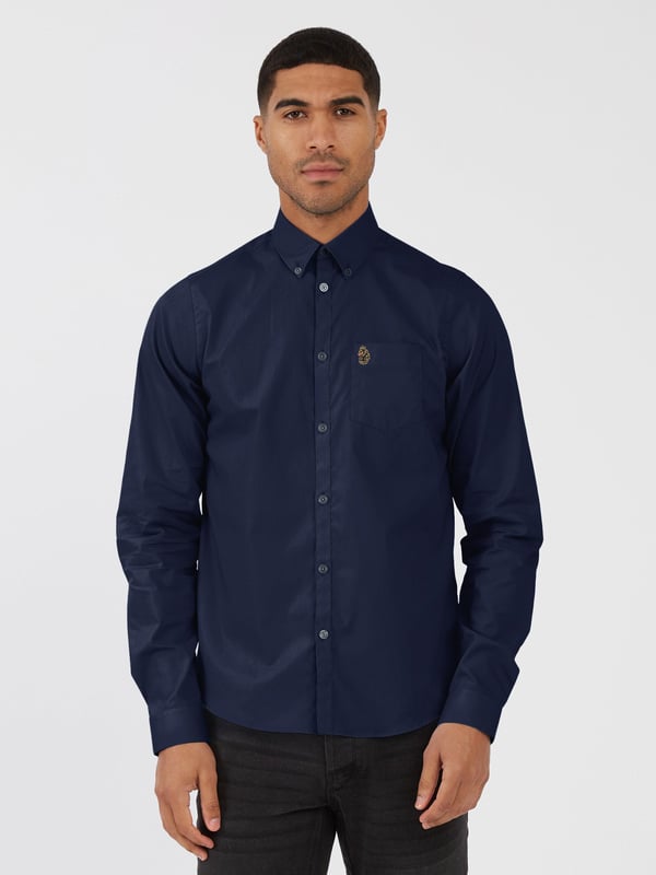 This classic LUKE long sleeved shirt is an essential item for your wardrobe, classically styled with a buttoned-down collar and a simple chest patch pocket. It is detailed with imitation river shell plastic buttons on the central front placket, running from hem to collar and is completed with the brand's iconic lion head embroidery on the left chest. Tailored fit. Iconic LUKE BLACK, GOLD, RED lion head embroidery. Iconic LUKE tri-colour trim tape. Left chest pocket detail-Imitation river shell plastic buttons. Central front placket. Button down collar detail at front and central at back. Back yoke detail and external back box pleat. Long sleeve with buttoned cuff.