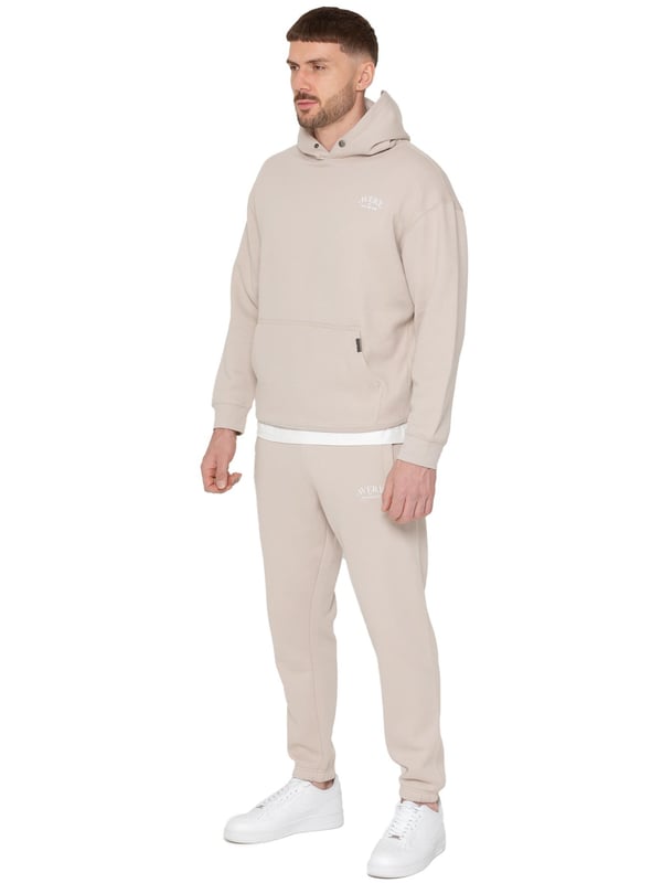 Presentamos el Conjunto de Chándal con Sudadera con Capucha Oversized Averè para Hombre de Enzo Milano, una mezcla perfecta de comodidad y estilo. Este set incluye una Sudadera con Capucha Oversized con un suave forro de felpa, un logotipo sutil en el pecho, un diseño audaz en la parte trasera y una capucha con botones a presión. Los Joggers de Corte Regular tienen una cintura elástica, cordones ajustables, bolsillos laterales y puños acanalados en los tobillos para un ajuste seguro. Ideal para relajarse o para salidas casuales, este chándal ofrece un estilo relajado y a la moda