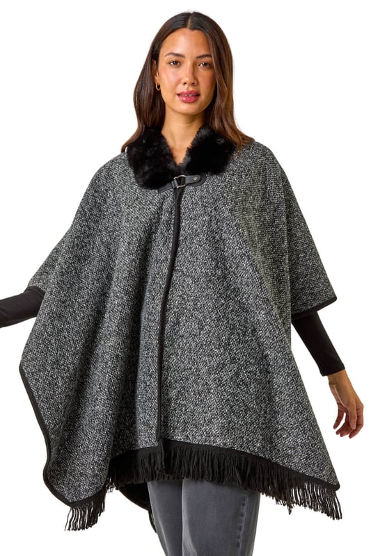 Faux Fur Fringe Hem Poncho from Roman. This style is ONE size.  Wrap up in style with this chic fringe detail poncho. Featuring a luxurious fur trim collar for added elegance and a trendy fringe hem for a playful finish, this poncho is the perfect layering piece for the Autumn/Winter season. Throw it on over your favourite knitwear and jeans for a fashion-forward look that will keep you both warm and stylish throughout the colder months!