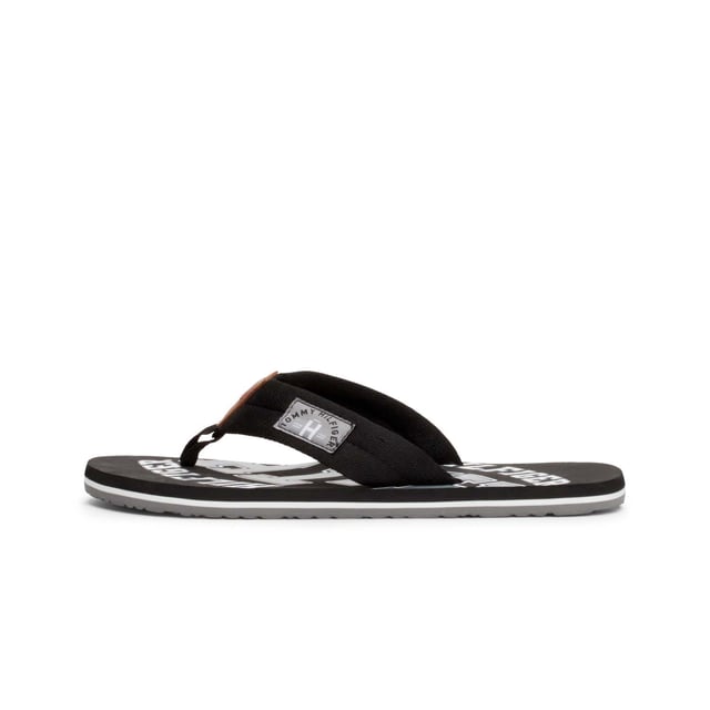 Mens Tommy Hilfiger Essential Beach Flip Flops in black.- Synthetic upper.- Slip on design.- Branded retro graphics.- Synthetic lining.- Rubber sole.- Ref.: FM0FM01369990