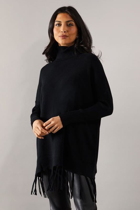 Chic fringed hem poncho design for effortless style
        Cosy roll neck for added warmth and sophistication
        Relaxed fit with dropped shoulders for comfortable wear
        Ribbed cuffs and hem for a polished finish
        Versatile knitted fabric suitable for various occasions
    
    Embrace effortless elegance with this fringed hem roll neck poncho from Wallis. Perfect for the fashion-forward woman who values both style and comfort, this piece offers a sophisticated silhouette that's ideal for casual outings and family gatherings. The relaxed fit and dropped shoulders create a flattering drape, while the roll neck adds a touch of refinement. Style it with slim-fit trousers and ankle boots for a chic daytime look, or layer it over a long-sleeved top with wide-leg trousers for a more dramatic ensemble. The fringed hem adds movement and interest, making it a standout piece in your wardrobe. Whether you're running errands or meeting friends for coffee, this poncho will keep you looking stylish and feeling cosy throughout the day.