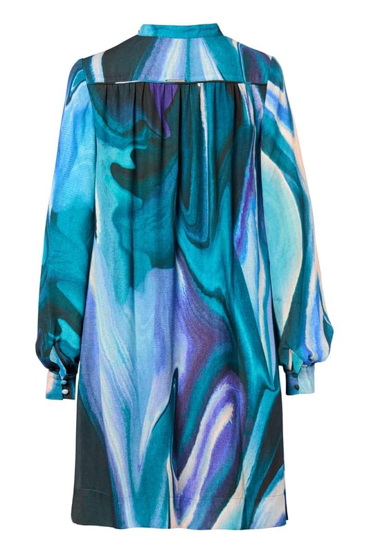 Stijlvolle damesjurk met verfijnde details en unieke printDe Dhalia Print Jurk is een schitterend en elegant kledingstuk met oog voor detail. De semi-transparante stof geeft een luchtig en verfijnd effect, terwijl de voering zorgt voor comfort en ondoorzichtigheid tijdens het dragen. De olieachtige print straalt in diverse kleuren, waaronder paars, aquagroen en een zwarte achtergrond, wat een eigentijdse en trendy uitstraling toevoegt. De prachtig uitgewerkte details, zoals het opstaande kraagje met plastron en bedekte knoopjes, de pofmouwen met manchetten en dezelfde verfijnde knoopjes, evenals de luxe plooien en piping bij de schoudernaden en rugpas, dragen bij aan de geraffineerdheid van het ontwerp. De jurk heeft een wijd uitlopende, lange blouse-stijl die zorgt voor een flatterend en elegant silhouet. De subtiele steekzakken in de zijnaden voegen een comfortabel element toe aan deze chique printjurk, waardoor de jurk zowel elegantie als functionaliteit combineert. Met zijn opvallende print, pofmouwen en prachtige details is deze jurk een veelzijdige aanvulling op elke garderobe. Op zoek naar extra warmte in de winter? Combineer de jurk met het aquagroene Parker vest voor een opvallende en stijlvolle look. Deze printjurk is absoluut een waardevolle toevoeging aan je nieuwe garderobe!"