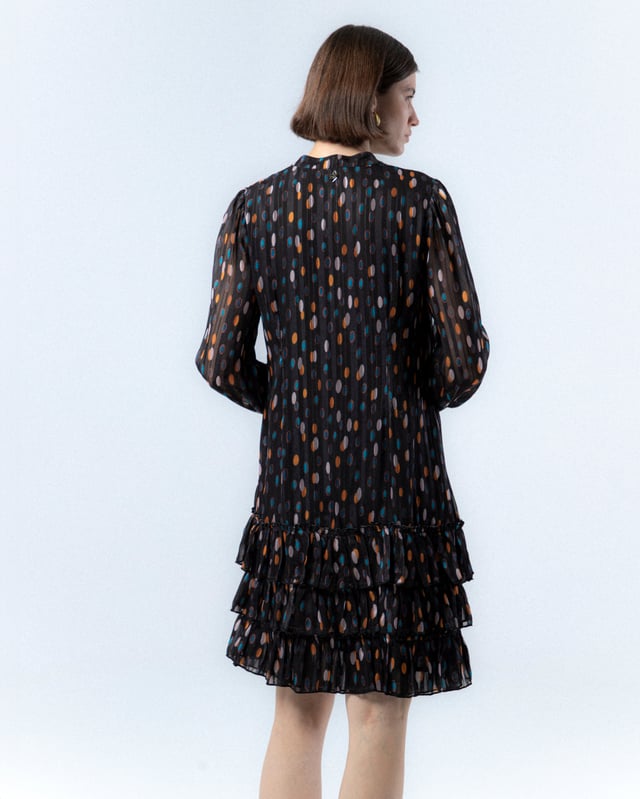 El vestido de lunares Alejandra, con su encantador estampado de lunares en tonos cálidos sobre fondo oscuro, te hará sentir la magia del otoño. Su diseño elegante y favorecedor es ideal para cualquier evento, añadiendo un toque de sofisticación y alegría a tu look.
 
 
 
 Vestido corto. 
 
 Abertura en escote con cierre de botones hasta la cintura. 
 
 Botones con aplique de piedras a mano. 
 
 Manga larga con puño elástico. 
 
 Bajo de tres volantes. 
 
 Tejido viscosa. 
 
 Estampado lunares.