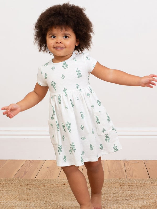 100% organic cotton | Proud to be certified to the Global Organic Textile Standard (GOTS) | Wildflower all-over print | Cream | Slub jersey (170-180 gsm) | Coconut button shoulder opening (up to and including size 3 years) | Side patch pockets | Short sleeved | Round neck | Made in Turkey | Machine washable at 40 degrees, or at 30 degrees to be kinder to the planet