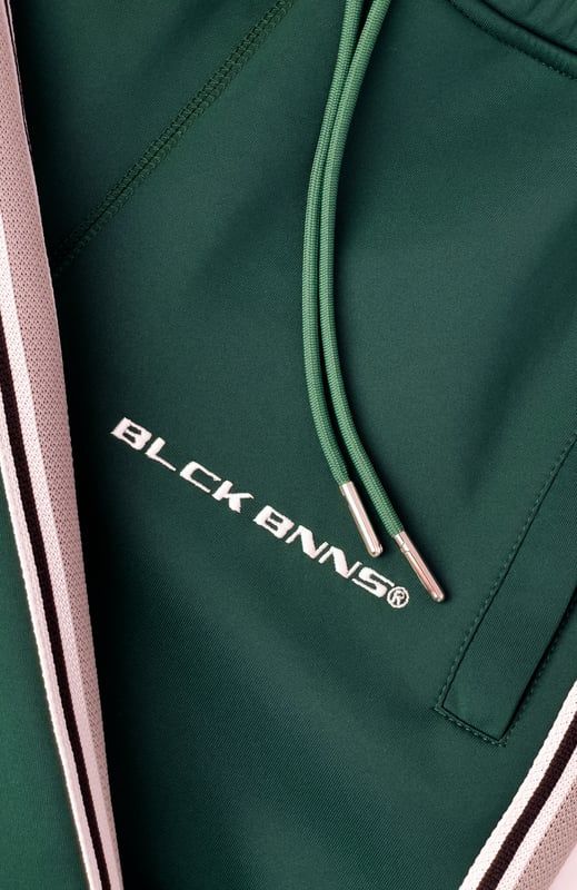 100% Polyester Elastischer Hosenbund mit Kordelzug Reißverschlusstaschen BLCK BNNS am rechten Bein Sportliches Streifenband an den Seiten Kombinierbar mit MIAMI TAPED TRACKTOP 