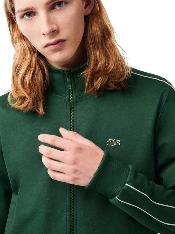 This regular-fit men's sweat jacket with contrasting stripes is a stylish basic. Made from high-quality material, it is extremely comfortable to wear. It fastens with a zipper that ends in a stand-up collar. The sleeves and hem are finished with plain-colored ribbed cuffs. Essentials can be stowed in the side slit pockets. The contrasting stripes on the sleeves provide a subtle visual highlight.