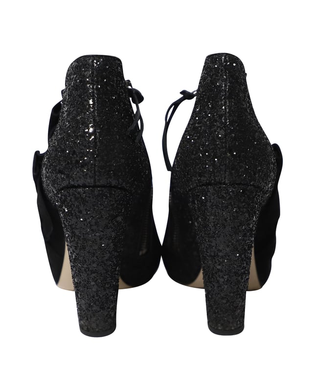 VINTAGE, UVP WIE NEU  
Diese schwarzen Peep-Toe-Stiefeletten von Miu Miu sind aus Wildleder gefertigt und mit Glitter überzogen, um deinen Stil gezielt zu heben. Sie sind mit Reißverschlüssen, Leder-Innensohlen ausgestattet und der Absatz misst 115 mm. Der Wildlederbereich der Schuhe ist so gestaltet, dass er wie ein Band aussieht, was einen zusätzlichen femininen Akzent setzt.

Miu Miu 115mm Glitter-Stiefeletten aus schwarzem Wildleder  
Zustand: Gut  
Nutzungsspuren: Starke Abnutzung an den Sohlen  
Material: Wildleder/Leder  
Größe: 38.5/US8.5  
Absatzhöhe: 115 cm  
SKU: 124358