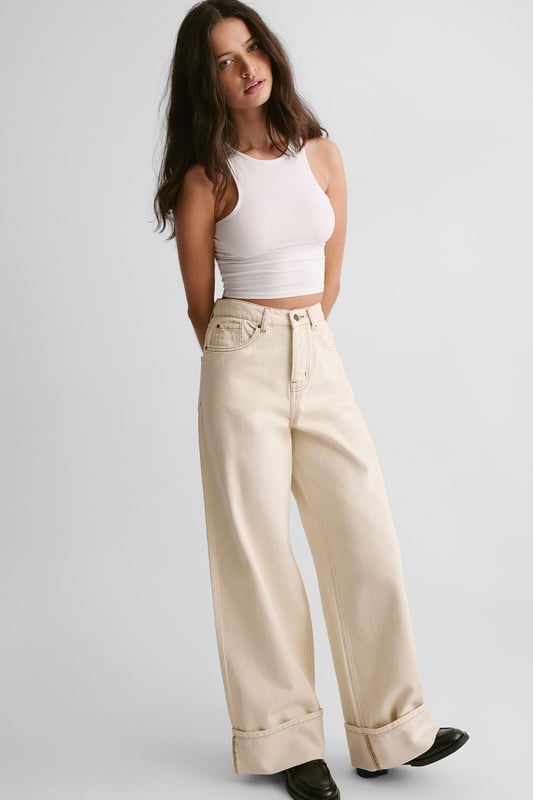 Wide-leg silhouette for a relaxed, on-trend look
        Distinctive turn-up cuffs adding a stylish twist
        High-waisted design for a flattering fit
        Classic five-pocket styling for practicality
        Versatile denim fabric suitable for various casual occasions
    
    The Denim Turn Up Jean from NastyGal presents a fresh take on a wardrobe staple. These jeans manifest a perfect blend of comfort and style, ideal for the fashion-forward individual seeking a versatile piece. The wide-leg silhouette paired with the high-waisted design creates a striking profile, while the turn-up cuffs add a touch of casual sophistication. Style these jeans with a fitted white vest top and chunky loafers for an effortlessly cool daytime look. For a more laid-back vibe, pair with a loose-fitting tee and trainers. These jeans are perfect for casual outings, family gatherings, or relaxed weekends about town. Their adaptable nature allows for easy transition from day to night - simply swap your flats for a pair of statement heels and add a blazer for an evening-ready ensemble. The Denim Turn Up Jean is a must-have piece that will quickly become a cornerstone of your casual wardrobe.