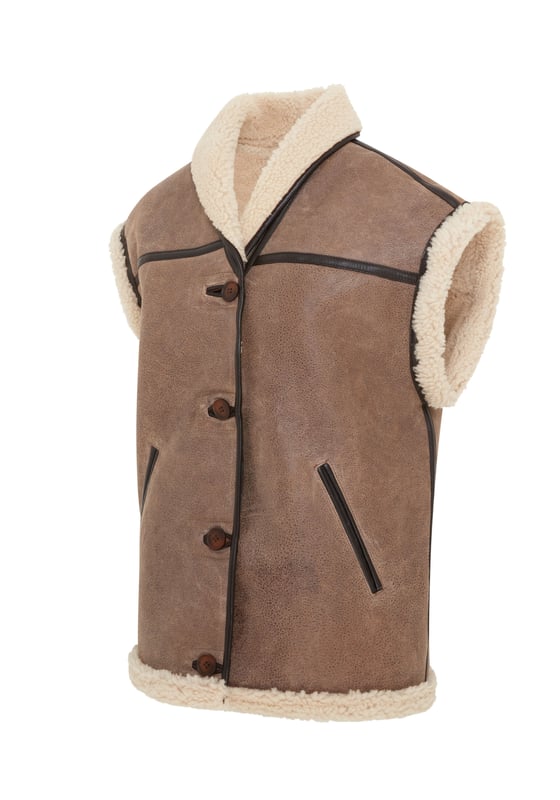 Añade una elegancia atemporal a tu vestuario de invierno con este chaleco de piel de oveja de borrego para mujer, una combinación armoniosa de sofisticación y comodidad. Con un lujoso color marrón tostado, forro de piel de oveja afelpada y detalles de ribetes de cuero. Perfecto para usar en capas, combina una calidez excepcional con un encanto atemporal. • Piel de oveja de borrego de doble cara de primera calidad • Forro de piel de oveja afelpada para una comodidad superior • Cierre con botones para un aspecto clásico • Detalles de ribetes de cuero para una mayor elegancia • 2 bolsillos laterales para mayor comodidad • Cuello versátil, se puede llevar hacia arriba o hacia abajo para darle estilo y calidez
