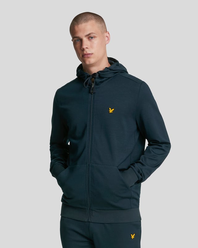 Ervaar comfort en stijl met de Lyle &amp; Scott Full Zip Dark Navy Hoodie. Gemaakt van 100% zacht katoen, biedt deze hoodie een ademende en comfortabele pasvorm, perfect voor dagelijks gebruik. De volledige ritssluiting maakt het gemakkelijk om te dragen in laagjes, terwijl de twee voorzakken handige opbergruimte bieden voor je essentials of een plek om je handen te warmen. De donkerblauwe tint zorgt voor een tijdloze look die moeiteloos bij elke outfit past. Of je nu een casual dagje uitgaat of thuis ontspant, deze hoodie combineert functionaliteit met klassieke stijl om je de hele dag comfortabel en zelfverzekerd te houden
