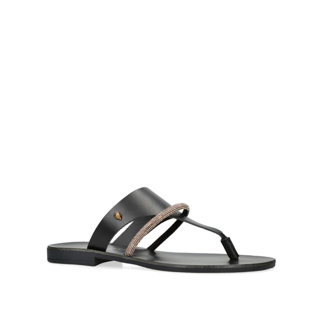 The KGL Strand is a black leather toe post sandal. There is a smaller, crystal embellished strap across the foot. The antiqued brass Eagle head sits on the outer side.