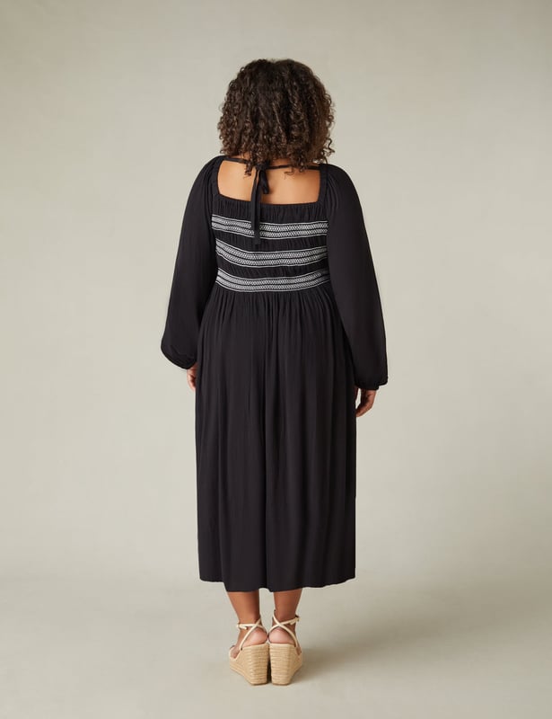 In classic black, this dress is cut from a soft, textured fabric thats so comfortable to wear. With elasticated shirring through the bodice in contrasting white, it has a flattering square-neck shape. Elastication around the neck and shoulder heads ensures comfort, while a cross-shoulder tie prevents the full-length sleeves from falling down. It has a stylish midaxi shape with a flowy skirt, making this the perfect warm weather piece.