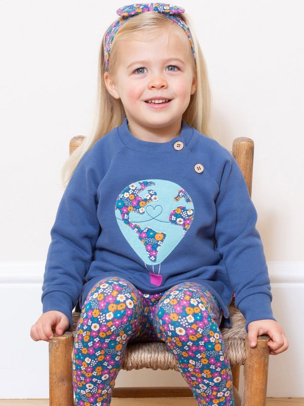 72 days and 25,000 miles later, Nellie Bly successfully circumnavigated the globe. This around the world sweatshirt is inspired by this incredible journey, which Nellie undertook to beat the popular fictional Jules Verne book “Around the World in Eighty Days”. Stylish and practical, with a lovely hot air balloon appliqué on super-soft navy blue brush back sweat fabric.
