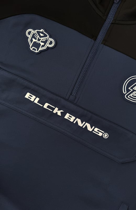 100 % poliéster Cuello alto con media cremallera Camino de convoy en el pecho Bolsillo lateral con cremallera en el brazo izquierdo Solapa distintiva de BNNS en color negro Dos bolsillos delanteros con cremallera Mangas a rayas Se puede combinar con RUMBLE TRACKPANTS