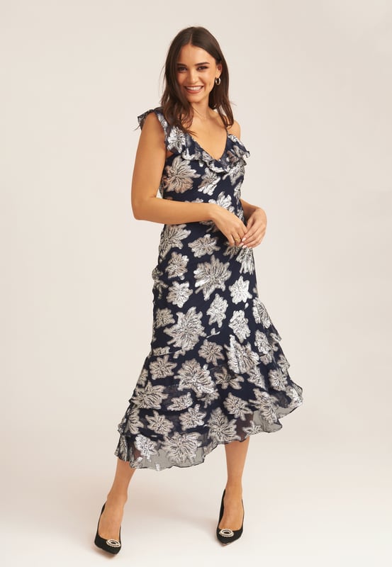 Saluda a este vestido midi con volantes florales imprescindible que es perfecto para cada ocasión. Si tienes una invitación para la boda de tu muñeca favorita, este vestido midi cumple todos los requisitos del código de vestimenta. Con un gran estampado floral y detalle de volante en el escote, ¿cómo podrías decir que no? Combina este vestido midi con tus tacones y tus accesorios favoritos para lograr un look que no pasará desapercibido.