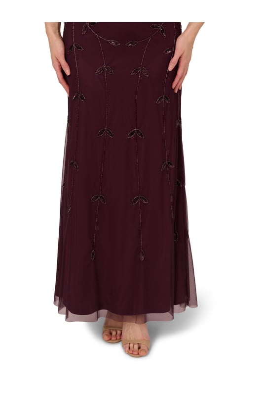 Put a little sparkle on display when you rock this sleeveless blouson gown. This formal dress features a sleeveless blouson bodice, deep v-neckline and back, and a soft skirt. Crafted with a luxe mesh fabric that is fully lined, this evening gown is embellished with sequin and beaded vines. The neckline and armholes of this gown are trimmed in beading for added sparkle. A hidden zipper closure at the centre back completes the design. This sleeveless beaded gown is a stunning look for a wedding guest or bridal party and pairs well with neutral or metallic accessories.