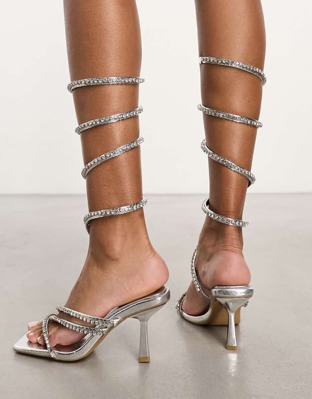 Simmi London Wide fit Freesia embellished leg wrap sandals in silver Shoes by Simmi Wide Fit Dress from the feet up Wrap-around design Diamante embellishment Open toe Flared heelSold By: Asos
