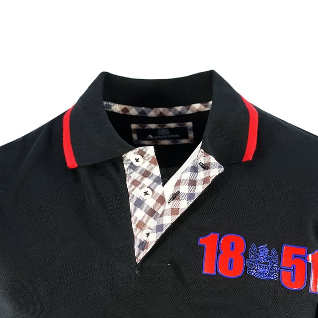 Aquascutum London 1851 Svart Polotröja. Se skarp ut i denna snygga Aquascutum Logo Black Polo Shirt, med en ikonisk märkeslogotyp. Från kontorsmöten till kvällsdrinkar, låt denna tidlösa klassiker omedelbart höja din vardagslook! Aquascutum London Broderad Aldis-logotyp omgiven av siffror för 1851 års grundande. 100% Bomull, Vanlig passform, Passar perfekt i storlek. Brittiskt flaggmärke på vänster ärm, Aquascutum Classic Check på undersidan av knapparna, krage, kortärmad, knappstängning. Modellkod: P01323 99