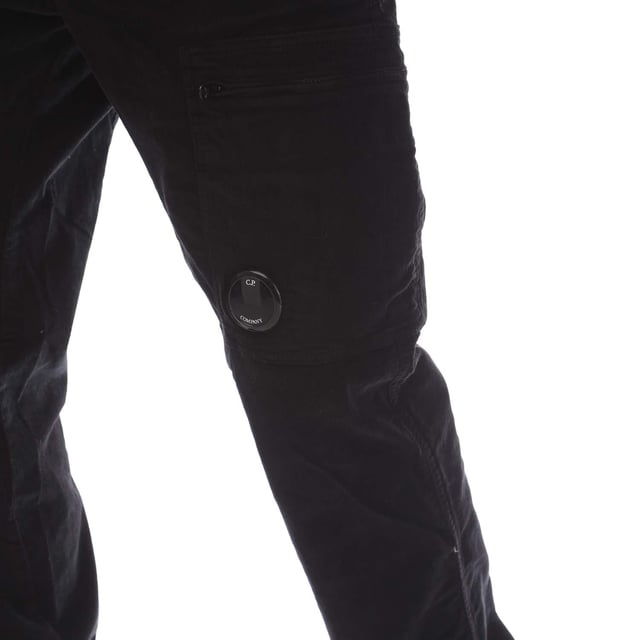 Mens C.P. Company Corduroy Lens Pants in black.- Adjustable drawstring at inner waistband.- Zip fly and button fastening.- Side welt pockets.- Rear patch pocket.- Cargo zip pocket with Lens detail.- Old dyed.- Regular fit.- 97% Cotton  3% Elastane.  Machine washable.- Ref: 17CMPA123A 006410O 999