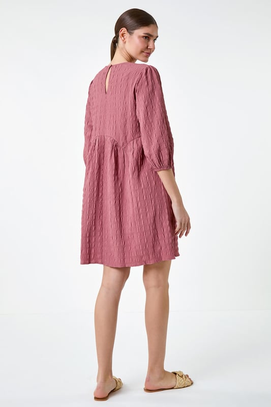 Bubble Textured A-Line Stretch Dress from Roman. Add pretty textures to your everyday collection this season, with this easy-to-wear A-line dress. Crafted from a stretch jersey fabric, this piece features a modest round neckline and 3/4 length sleeves, finished with elasticated cuffs. An empire waistline ensures a flattering and comfortable fit, while the all-over texture provides interest throughout. Pair with sandals and a denim jacket for a laid-back look, or add wedges and a sun hat for a day at the beach club!
