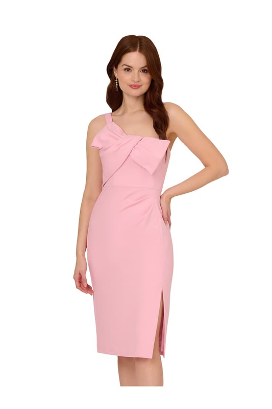 Trend-forward bow details add a fun twist to this cute short dress. This cocktail dress features a one shoulder neckline, sheath silhouette, and a bow accent at the bust with draped detailing. Designed from knit crepe fabric with some stretch, this party dress has a side slit at the skirt for easy movement. A hidden zipper closure at the side completes this one shoulder dress. Style this dress, which scales from semi-formal to formal, with nude heels and metallic accessories for a polished look.
