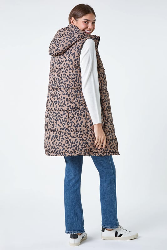 Animal Print Longline Hooded Gilet from Roman. Gilets are the perfect option for the transitional seasons, providing just the right amount of warmth for unpredictable weather. Cut from a woven fabric this gilet features a cosy funnel neck and a front zip fastening for a secure fit. A practical hood is finished with a drawstring cord for an adjustable fit, while zipped pockets provide space for your everyday essentials. Adorned in a fun animal print this piece is padded for extra warmth. Pair with relaxed denim and knitwear with either boots and trainers for trendy everyday style!